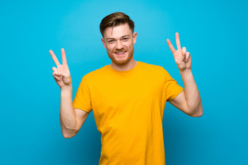 Fototapeta premium Redhead man over blue wall showing victory sign with both hands