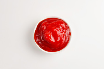 Ketchup in white plate on white background.