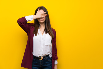 Young woman over yellow wall covering eyes by hands. Do not want to see something