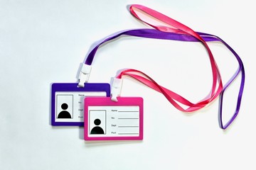 Two empty badges, pink and purple, with satin ribbons lying crosswise. On a light background in an overlap on each other in the center.