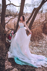 Fototapeta premium Beautiful romantic european girl with guitar with flowers inside, posing outdoors. Concept of music and nature. Spring time.