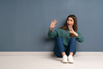 Young woman sitting on the floor nervous and scared