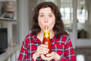 Healthy lifestyle, vitamin drinks and diet concept - close up of happy woman drinking juice at home