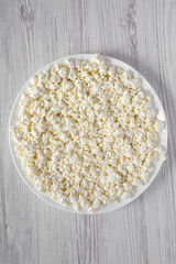 Homemade cottage cheese on a white plate, overhead view. From above, top view.