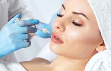 The doctor cosmetologist makes Lip augmentation procedure of a beautiful woman in a beauty...