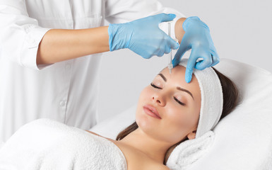 Fototapeta na wymiar The doctor cosmetologist makes the Rejuvenating facial injections procedure for tightening and smoothing wrinkles on the face skin of a beautiful, young woman in a beauty salon.Cosmetology skin care.