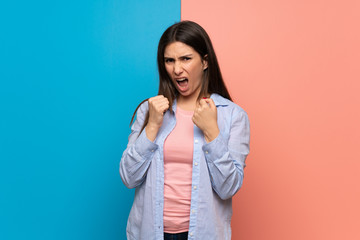 Young woman over pink and blue wall frustrated by a bad situation