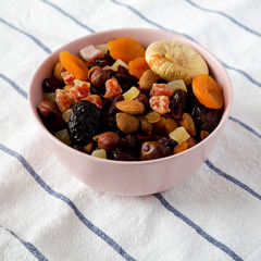 Dried fruits and nuts in a pink bowl, side view. Close-up.