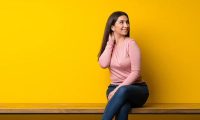 Young woman sitting on table thinking an idea while scratching head