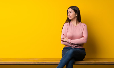 Young woman sitting on table with confuse face expression while bites lip
