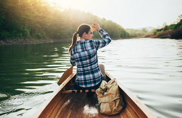 Rear view of travel woman rowing the boat at sunset