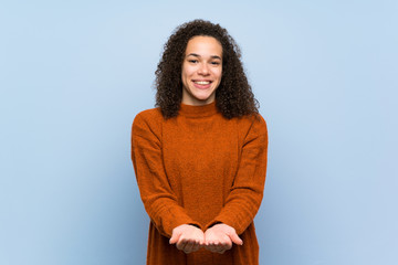 Dominican woman with curly hair holding copyspace imaginary on the palm to insert an ad