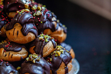profiteroles coated with chocolate and garnished with sprinkles and nuts