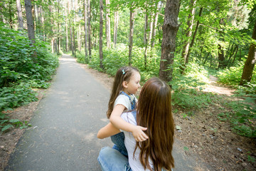 Nature, motherhood and child concept - Happy mother and little daughter have fun in green park