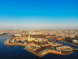 Obraz premium Beautifull aerial view of the Petropavlovsky fortress in sunny spring day. Golden tall spire of famous Peter and Paul Cathedral on the blue sky background. Historical centre of St. Petersburg, Russia.