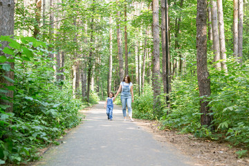 Family, leisure and nature concept - Portrait of mother with her little daughter walking in the green park in summer