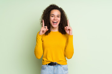 Dominican woman over isolated green background pointing up a great idea