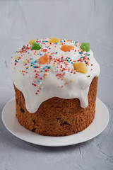 Easter Orthodox Easter cake with white icing and multi-colored candied fruits on a gray background