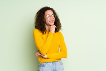 Dominican woman over isolated green background with glasses and smiling