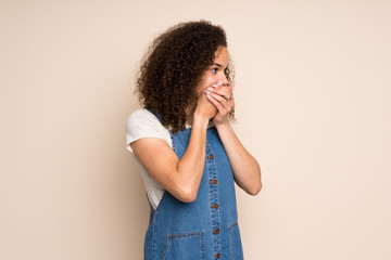 Dominican woman with overalls covering mouth and looking to the side