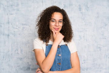 Dominican woman with overalls over grunge wall laughing