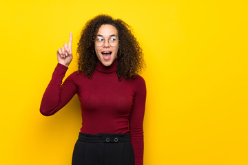 Dominican woman with turtleneck sweater intending to realizes the solution while lifting a finger up