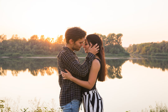 Relationship, love and nature concept - Attractive woman and handsome man hugging and kissing over water background