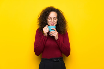 Dominican woman with turtleneck sweater holding a hot cup of coffee