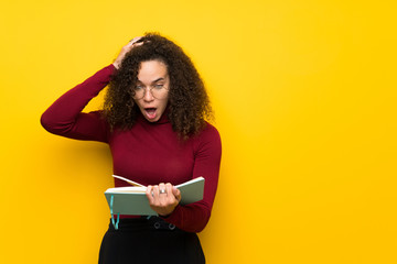 Dominican woman with turtleneck sweater surprised while enjoying reading a book