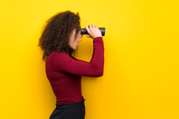 Dominican woman with turtleneck sweater and looking in the distance with binoculars