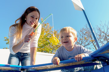 Happy little boy playing in fishing game with his mother. Happiness chilehood play concept. High...