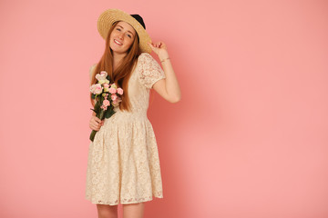 Beautiful, idyllic girl with straw hat and bouquet of flowers.