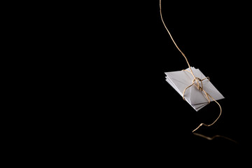 white envelope tied with a rope, falls on a black background