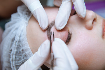 Process of making eyebrows. Pretty woman with closed eyes on the procedure