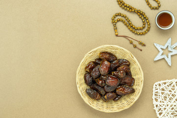 Table top view aerial image of decorations Ramadan Kareem holiday background.Flat lay date with rosary & lighting and cup of tea.Halal meal set for fasting is obligatory for Muslim on black wooden.