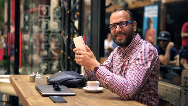 Portrait of happy man with tablet computer sitting in cafe in city
