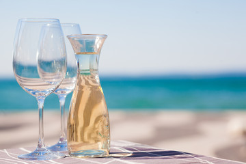The carafe of white wine and a glass of wine by Garda Lake beach
