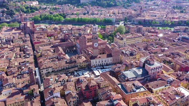 Aerial drone video of iconic Erbe square or piazza Erbe featuring Lamberti Tower in the heart of Verona, Veneto, Italy