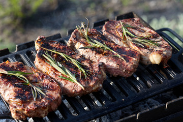 Juicy beef steaks cooking on grill outdoors
