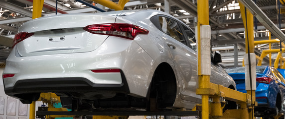 Automotive factory. The body of a modern white car on the lift. Conveyor production line of...