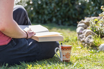 Person liest Buch im Garten