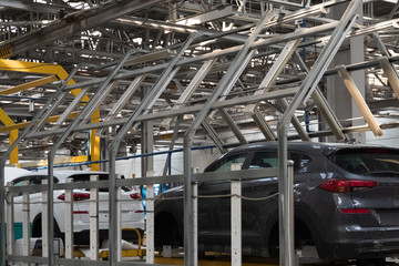 Automotive factory. The body of a modern black car on a lift. Conveyor production line of vehicles. Background for banner or header site.