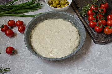 Traditional Italian focaccia with tomatoes, olives and rosemary. Focaccia cooking process, ingredients. Focaccia dough.