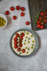 Traditional Italian focaccia with tomatoes, olives and rosemary. Focaccia cooking process, ingredients. Focaccia dough.