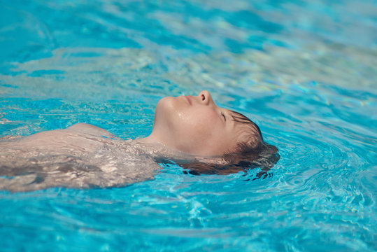 Swimming in pool. Boy learning to swim backstroke.