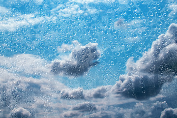 Water drops on glass against background of sky with storm clouds