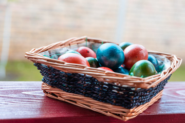 Easter eggs in a knitted basket on a wooden background
