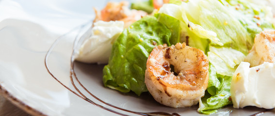 Restaurant healthy food, salad, arugula with shrimps and cherry tomatoes, covered with parmesan, closeup at plate
