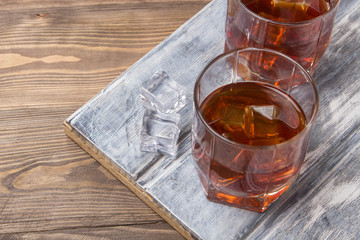 Two glasses of whiskey with ice on a beautiful wooden background