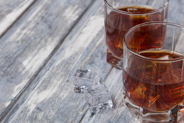 Two glasses of whiskey with ice on a beautiful wooden background